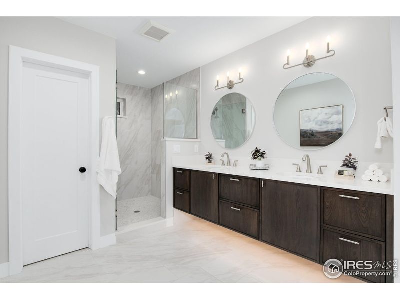 Primary bathroom with double vanity, linen closet, quartz counter, and luxury walk-in shower with penny accent tiling.