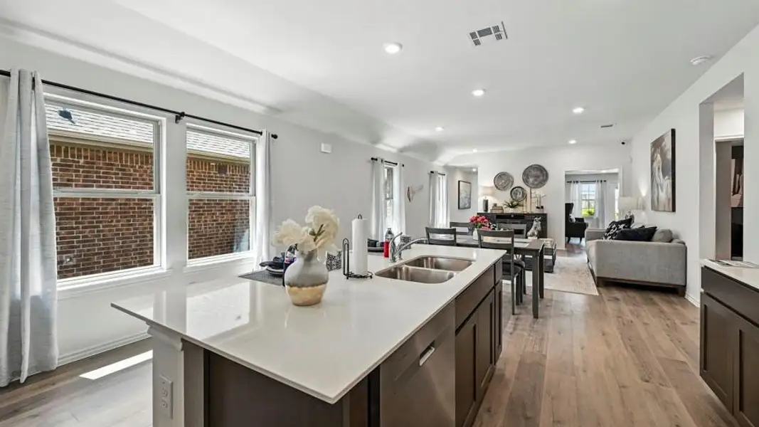 Kitchen island with integrated double basin sink, light-toned countertop, and dark wood-finish cabinetry