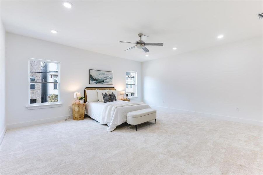 Carpeted bedroom with ceiling fan and multiple windows