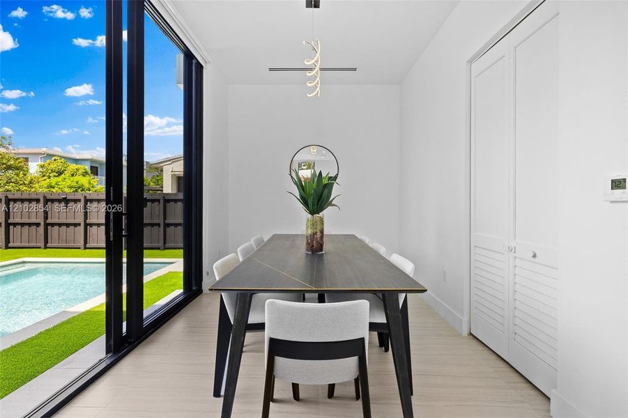 Floor-to-ceiling sliding glass doors, neutral tile flooring, modern pendant lighting, and white louvered closet doors