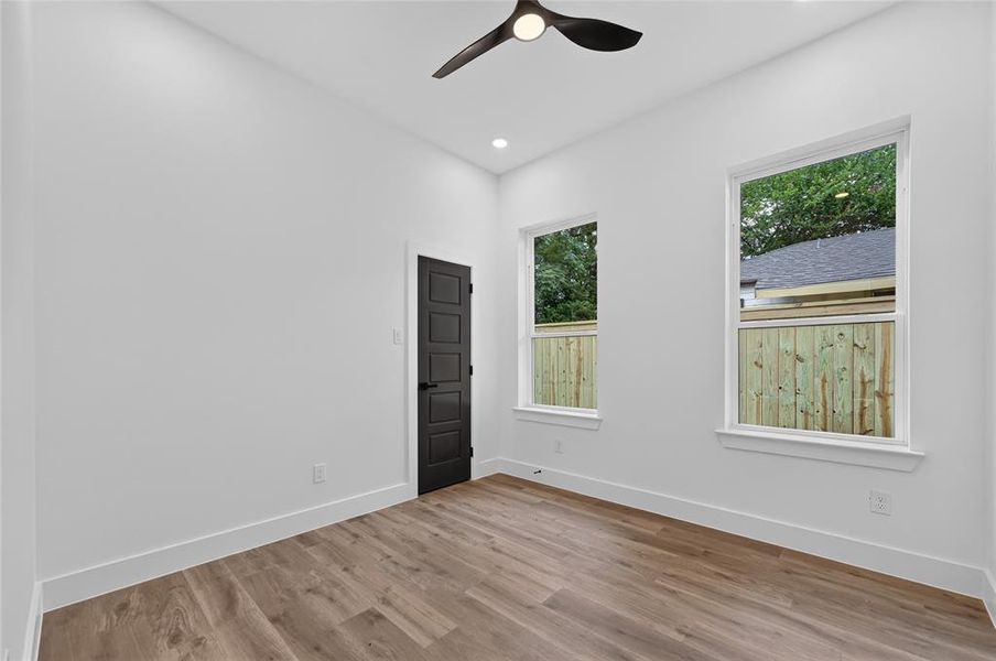 Room featuring light wood-finish flooring, white baseboards, and bright white walls Room featuring light wood-finish flooring, white baseboards, and bright white walls
