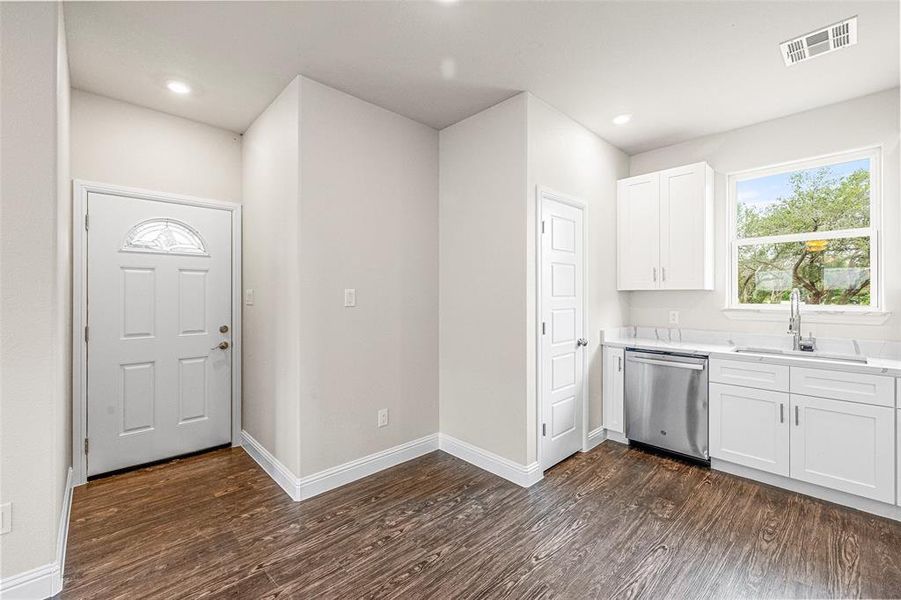 Kitchen with dishwasher, sink, dark hardwood / wood-style flooring, and white cabinetry