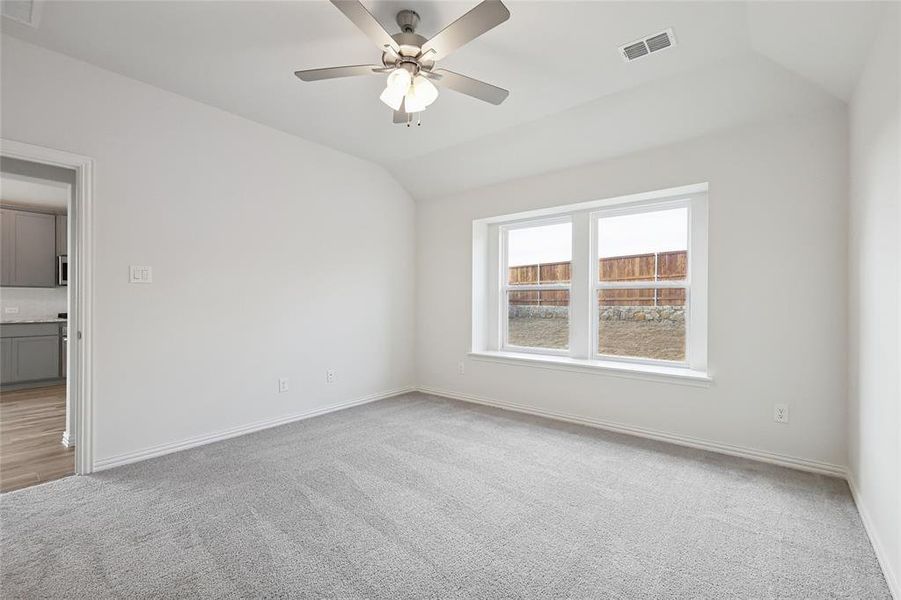 Unfurnished room featuring vaulted ceiling, light carpet, and a ceiling fan