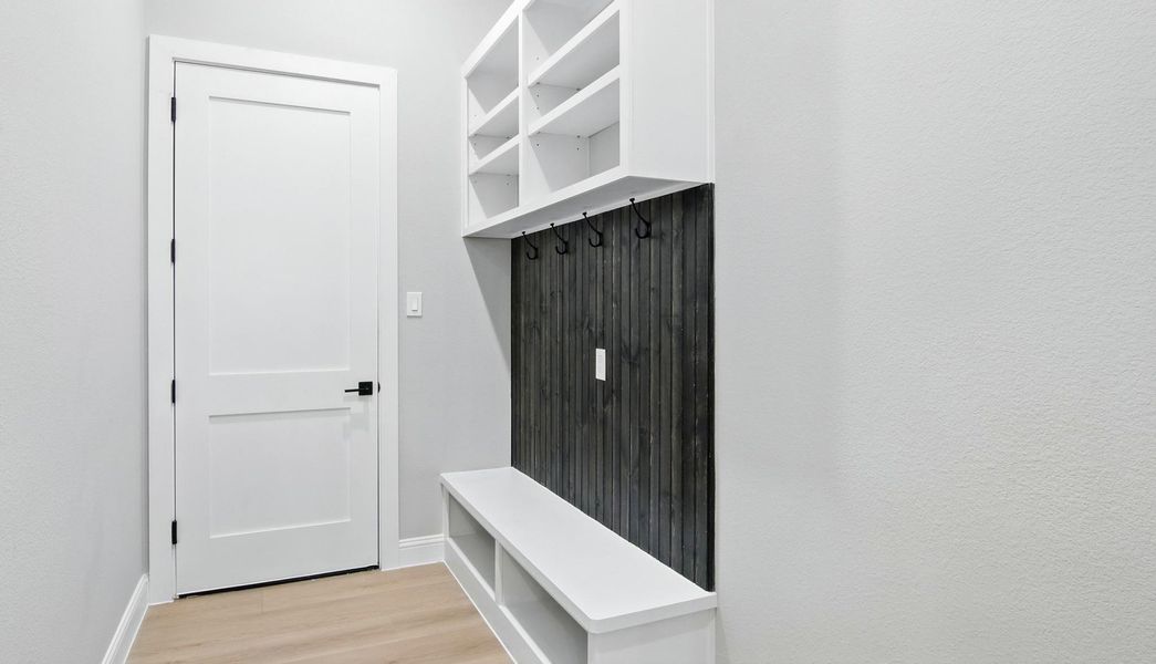 This practical and stylish mudroom offers the perfect space to stay organized. Featuring built-in cubbies, open shelving, and a bench with storage, it’s ideal for keeping shoes, bags, and outerwear neatly tucked away. The dark wood accent wall with coat hooks adds warmth and contrast against the crisp white cabinetry and light wood flooring, creating a modern yet welcoming entry point from the garage. This practical and stylish mudroom offers the perfect space to stay organized. Featuring built-in cubbies, open shelving, and a bench with storage, it’s ideal for keeping shoes, bags, and outerwear neatly tucked away. The dark wood accent wall with coat hooks adds warmth and contrast against the crisp white cabinetry and light wood flooring, creating a modern yet welcoming entry point from the garage.