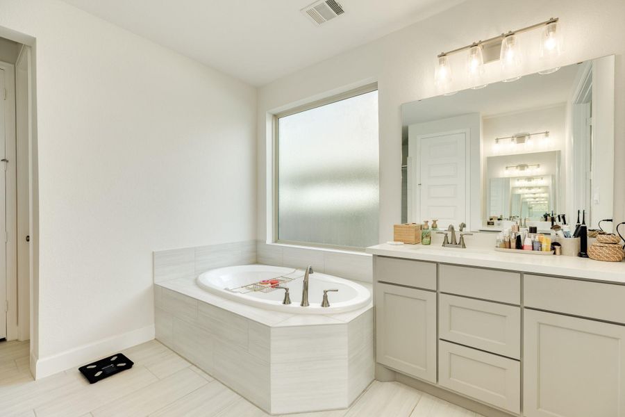 Primary bath features an expansive double vanity with ample under-cabinet storage, sleek modern lighting fixtures, and elegant quartz countertops. Primary bath features an expansive double vanity with ample under-cabinet storage, sleek modern lighting fixtures, and elegant quartz countertops.