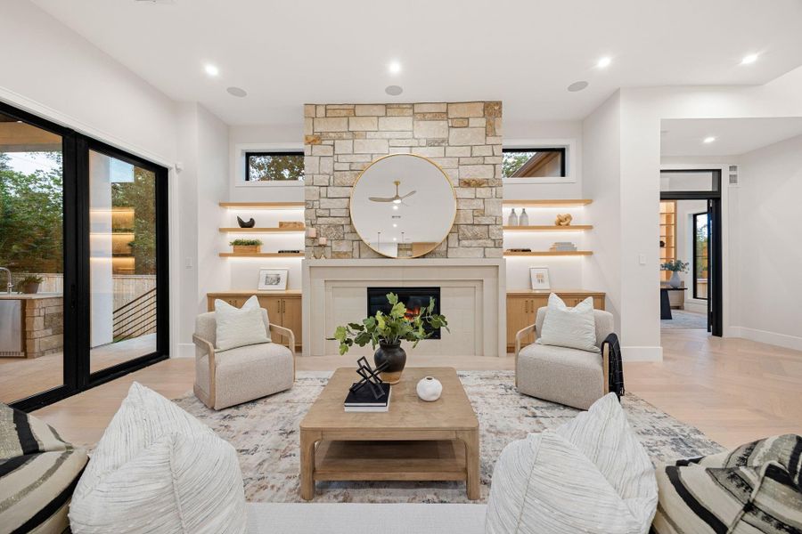 A perfectly balanced view of the central fireplace wall, where clean symmetry meets natural texture. The stone surround, custom cabinetry, and softly lit shelving create a layered, cohesive look that draws the eye. Subtle detailing and warm finishes add depth without overwhelming the space, resulting in a refined focal point that anchors the entire living area.