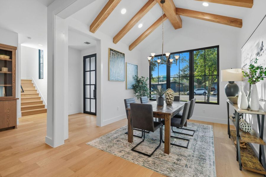 Dining space featuring plenty of natural light, beam ceiling, light wood-style flooring, a chandelier, and stairway