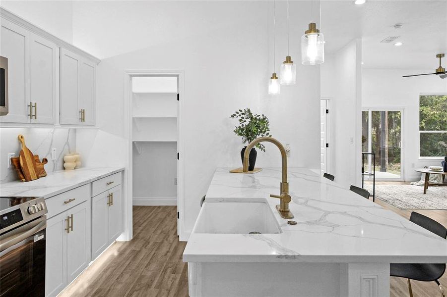 Kitchen with white cabinetry, light wood finished floors, electric range, light stone countertops, and pendant lighting Kitchen with white cabinetry, light wood finished floors, electric range, light stone countertops, and pendant lighting