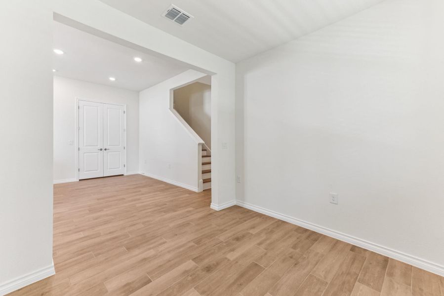 Empty room featuring light wood-style flooring, recessed lighting, and stairs Empty room featuring light wood-style flooring, recessed lighting, and stairs