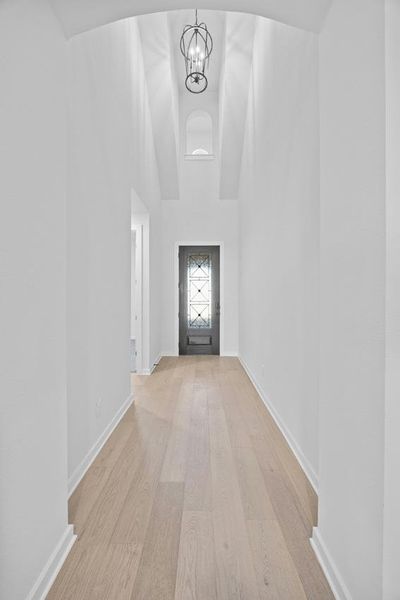 Entryway featuring light wood-style flooring, a chandelier, and high vaulted ceiling Entryway featuring light wood-style flooring, a chandelier, and high vaulted ceiling