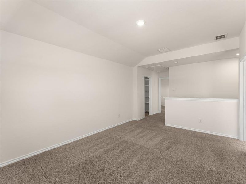 Carpeted spare room featuring vaulted ceiling