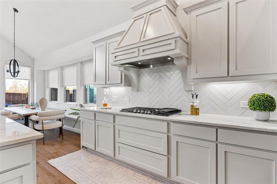 Kitchen with custom exhaust hood, tasteful backsplash, a notable chandelier, vaulted ceiling, and stainless steel gas stovetop