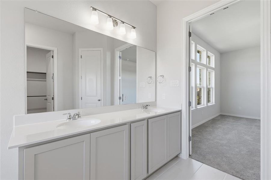 Bathroom with double vanity, light carpet, and light tile patterned flooring Bathroom with double vanity, light carpet, and light tile patterned flooring