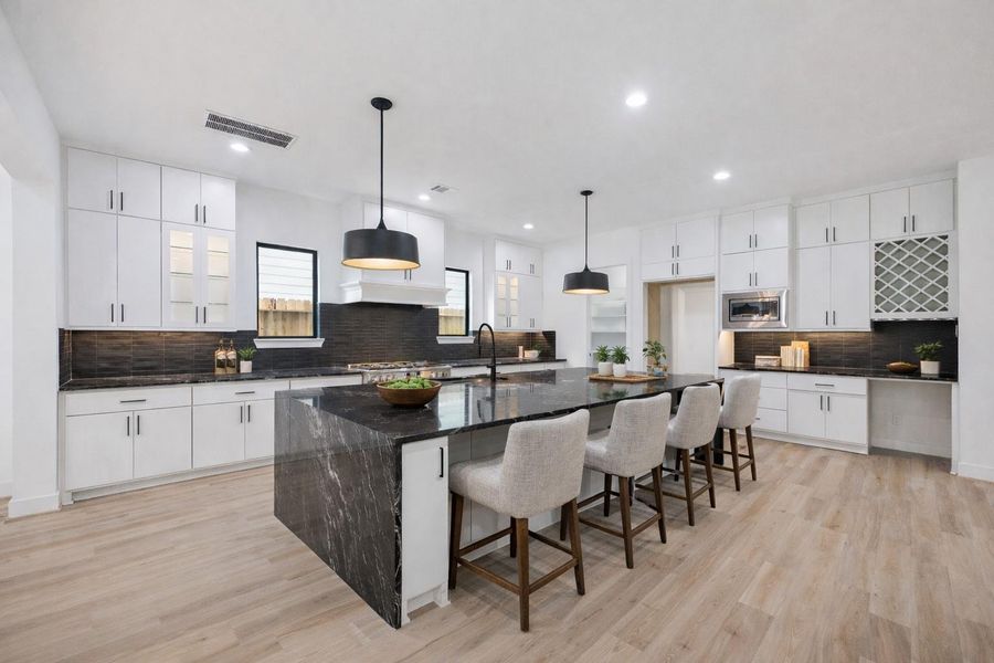 Bold contrast and streamlined design define this chef-worthy kitchen, featuring a dramatic waterfall-edge island, black tile backsplash, and modern pendant lighting. Ample cabinetry, a built-in wine rack, and pantry offer form and function. *Virtually Staged* Bold contrast and streamlined design define this chef-worthy kitchen, featuring a dramatic waterfall-edge island, black tile backsplash, and modern pendant lighting. Ample cabinetry, a built-in wine rack, and pantry offer form and function. *Virtually Staged*