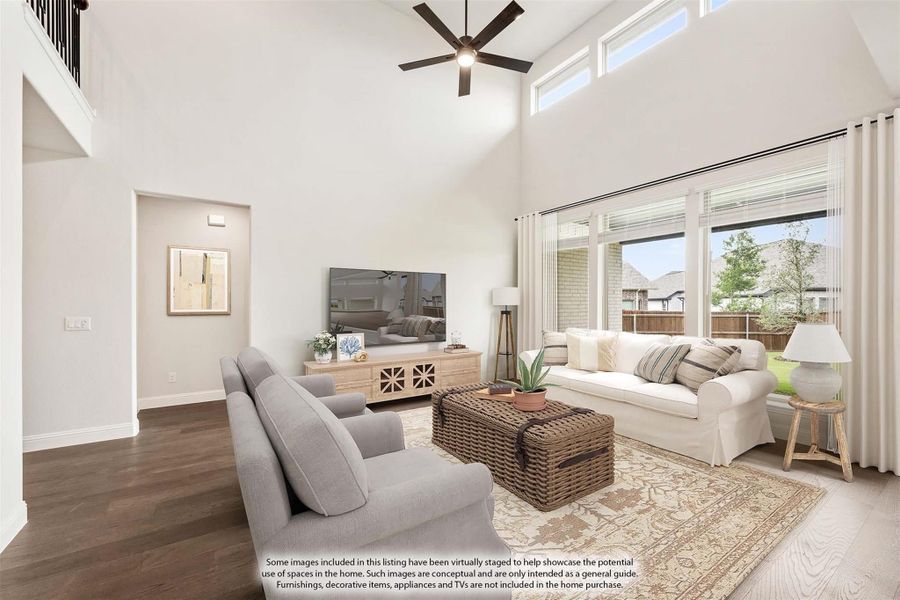 Living room with two-story vaulted ceiling, ceiling fan, large windows, hardwood floors, and neutral furniture. Living room with two-story vaulted ceiling, ceiling fan, large windows, hardwood floors, and neutral furniture.
