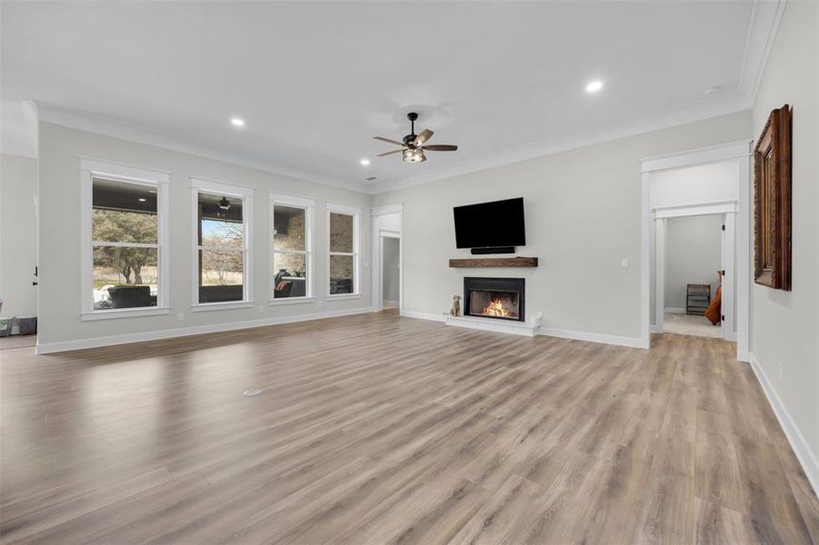 Unfurnished living room featuring ceiling fan, crown molding, and light hardwood / wood-style floors