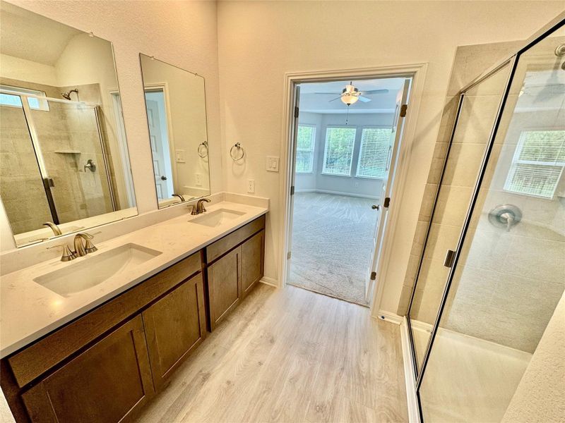 Bathroom with a shower stall, double vanity, wood finished floors, and ceiling fan Bathroom with a shower stall, double vanity, wood finished floors, and ceiling fan