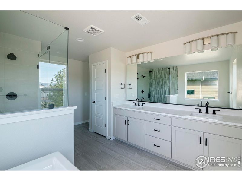 A true retreat - primary bathroom with double vanities, large soaking tub, and spacious shower plus private toilet room