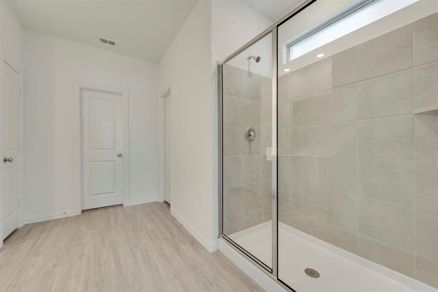 Bathroom with a shower with shower door and hardwood / wood-style floors