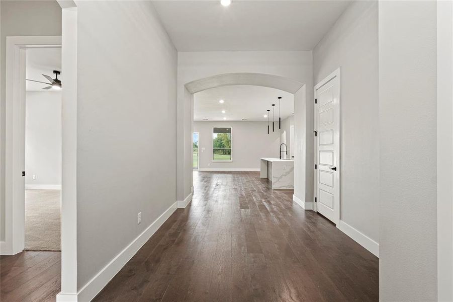 Hallway featuring arched walkways, dark wood-style flooring, and recessed lighting