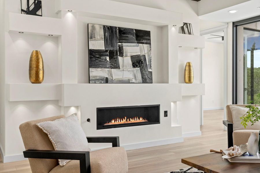 Living room featuring light wood-style floors, a glass covered fireplace, and recessed lighting