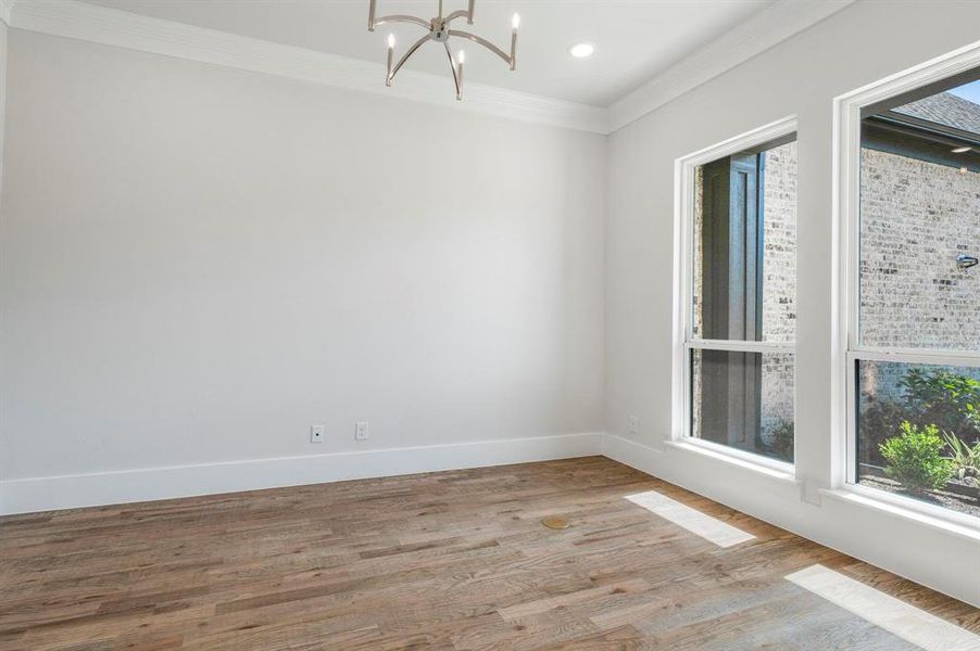 Unfurnished room with a notable chandelier, light hardwood / wood-style floors, and crown molding