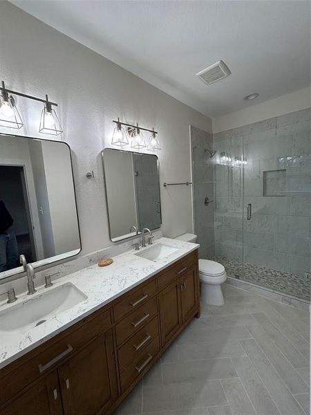 Master bathroom featuring tile patterned floors, vanity, an enclosed shower, and toilet