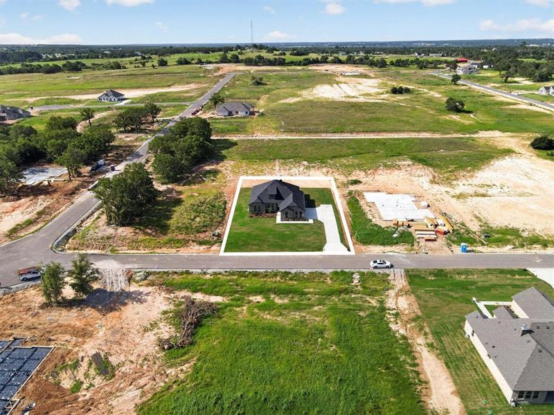 Newly constructed residence with a dark gray roof, situated on a verdant lot