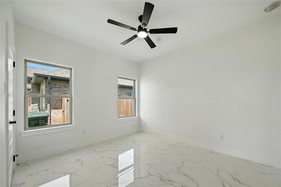 Empty room with marble finish floors and a ceiling fan
