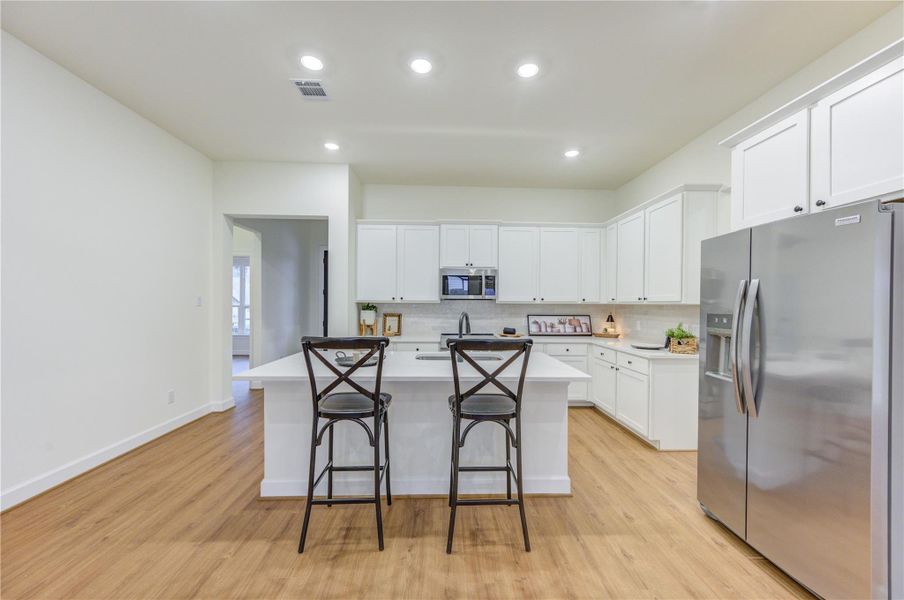 This stunning kitchen boasts sleek white cabinetry, modern stainless steel appliances, and a spacious island with seating, perfect for culinary adventures and entertaining guests. This stunning kitchen boasts sleek white cabinetry, modern stainless steel appliances, and a spacious island with seating, perfect for culinary adventures and entertaining guests.