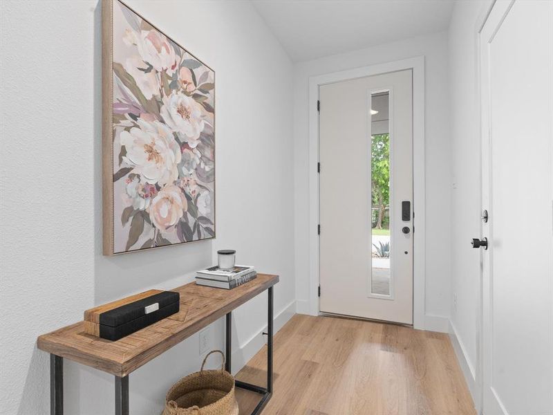 Doorway to outside featuring baseboards and light wood-style flooring Doorway to outside featuring baseboards and light wood-style flooring