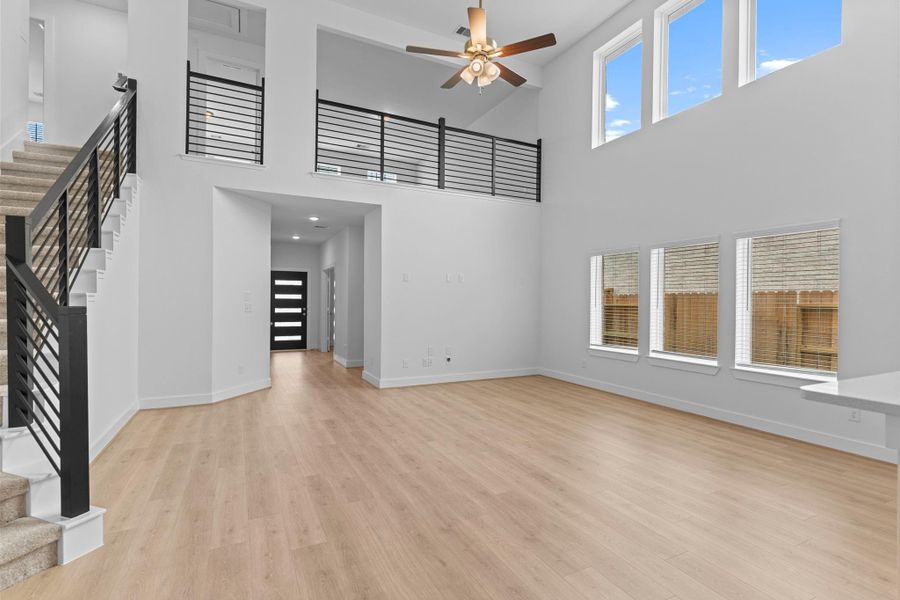 The two-story family room captures natural light beautifully through its full wall of windows, making the space feel bright, welcoming, and perfect for any style of decor. **Image Representative of Plan Only and May Vary as Built**.