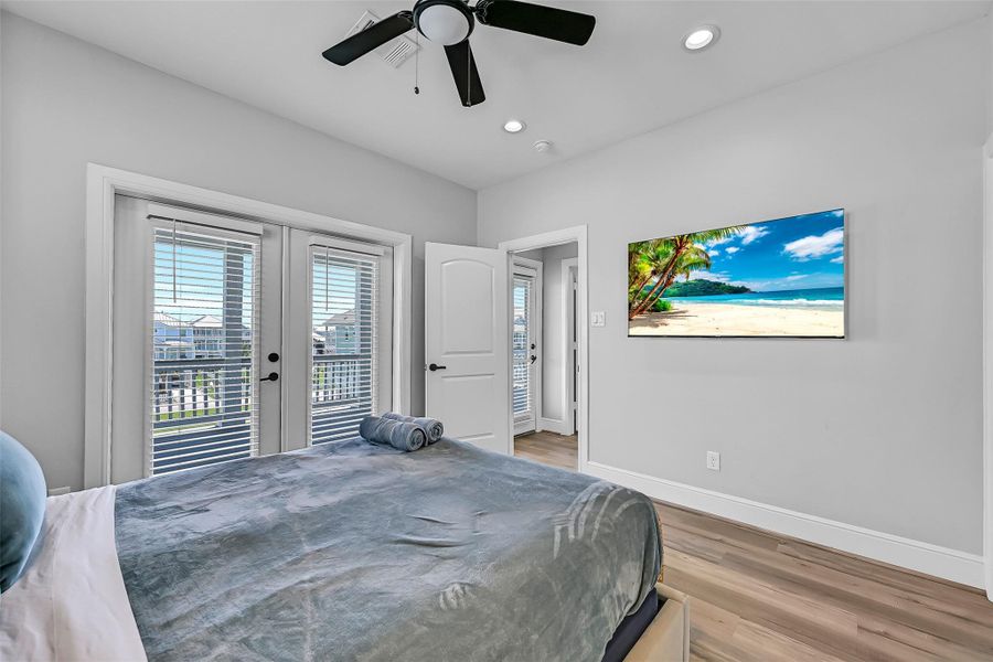 Another view of the first upstairs primary bedroom. Wake up to bright interiors, elevated ceilings, and a layout that feels open without losing warmth or comfort.  Walk outside to enjoy the beautiful deck and the ocean views.
