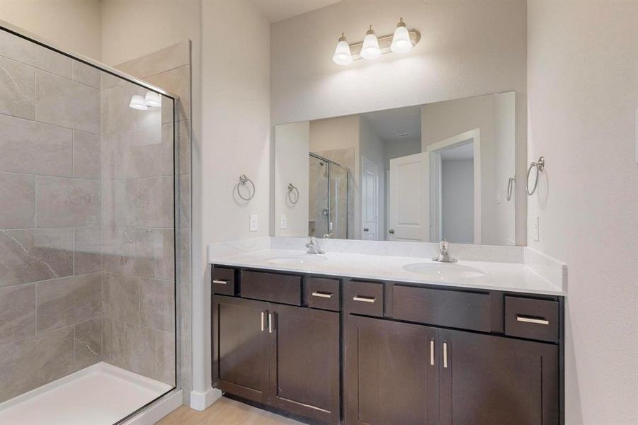 Bathroom with a shower stall, double vanity, and light wood-style floors
