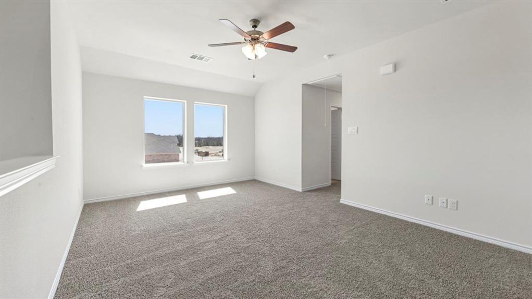 Carpeted empty room featuring a ceiling fan and lofted ceiling