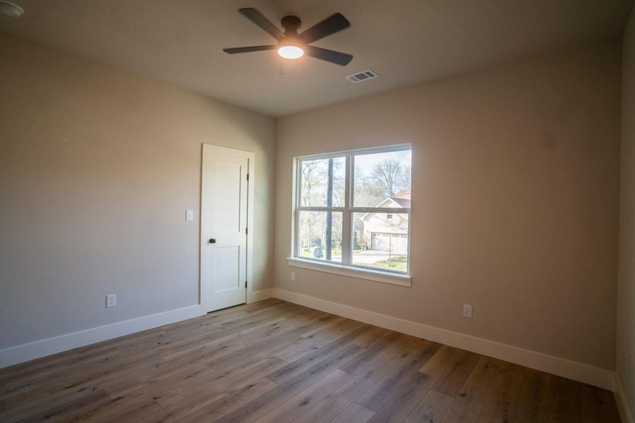 Spare room featuring wood finished floors, a ceiling fan, visible vents, and baseboards