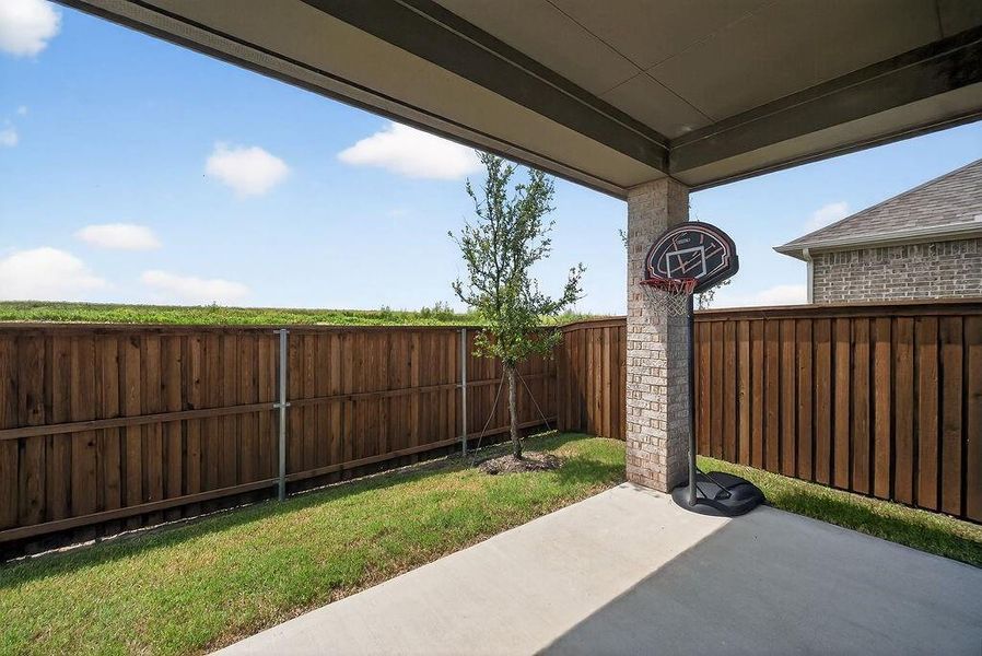 Covered patio featuring a concrete surface, a brick support column, and a wood privacy fence enclosing a grassed yard
