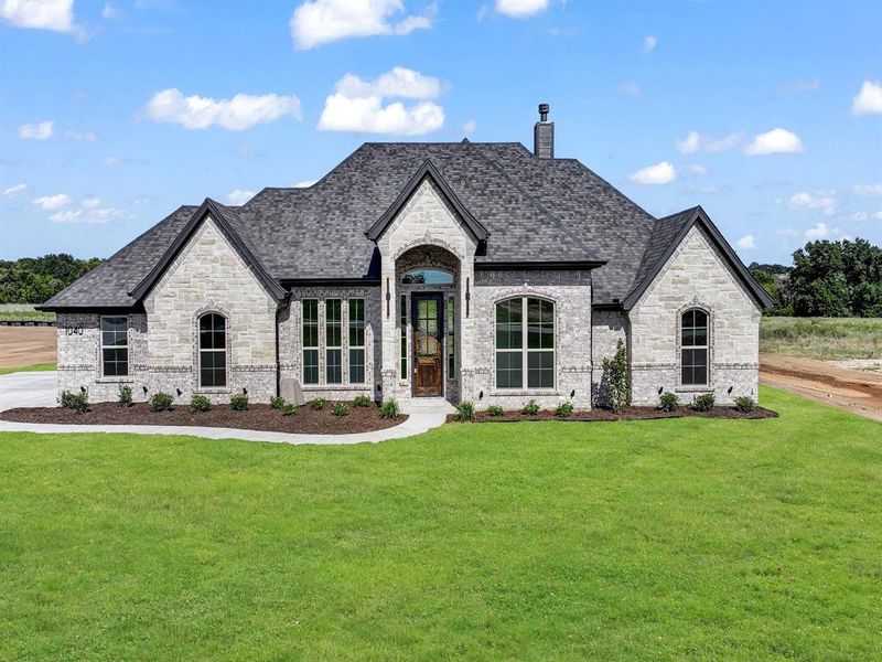 French country inspired facade featuring stone siding, a front yard, and a chimney French country inspired facade featuring stone siding, a front yard, and a chimney