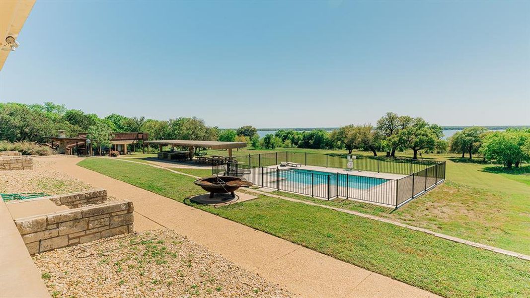 View of swimming pool featuring a patio area, a fire pit, and view of scattered trees