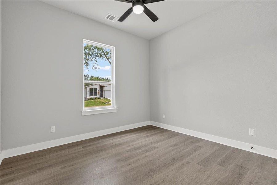 A well-lit bedroom features durable hardwood flooring and a refreshing ceiling fan. A well-lit bedroom features durable hardwood flooring and a refreshing ceiling fan.