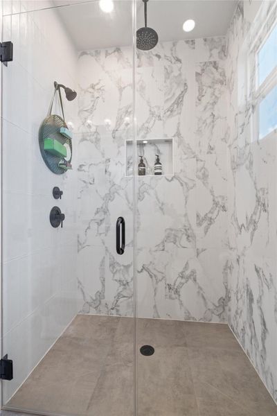 A well-appointed shower space showcases sleek glass enclosures and exquisite marble-patterned tile work. A well-appointed shower space showcases sleek glass enclosures and exquisite marble-patterned tile work.