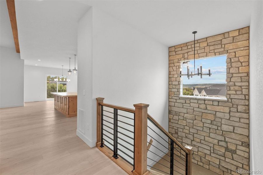 The stairwell to the lower level features a wood-and-iron banister and a limestone accent wall - a defining material carried throughout the home.
