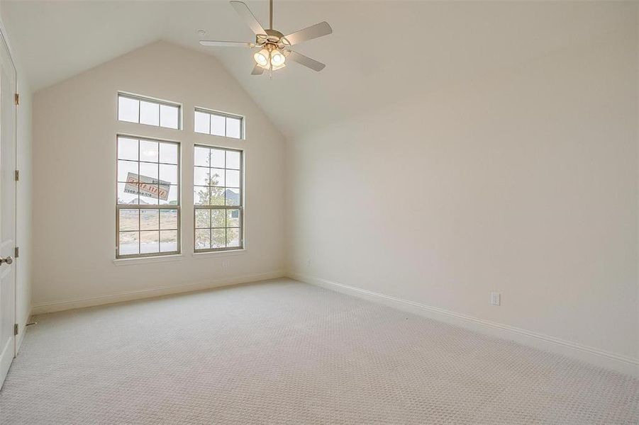 Additional living space with ceiling fan, light colored carpet, and vaulted ceiling