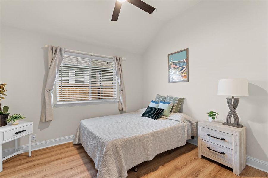 Bedroom featuring vaulted ceiling, light wood-style floors, and a ceiling fan Bedroom featuring vaulted ceiling, light wood-style floors, and a ceiling fan