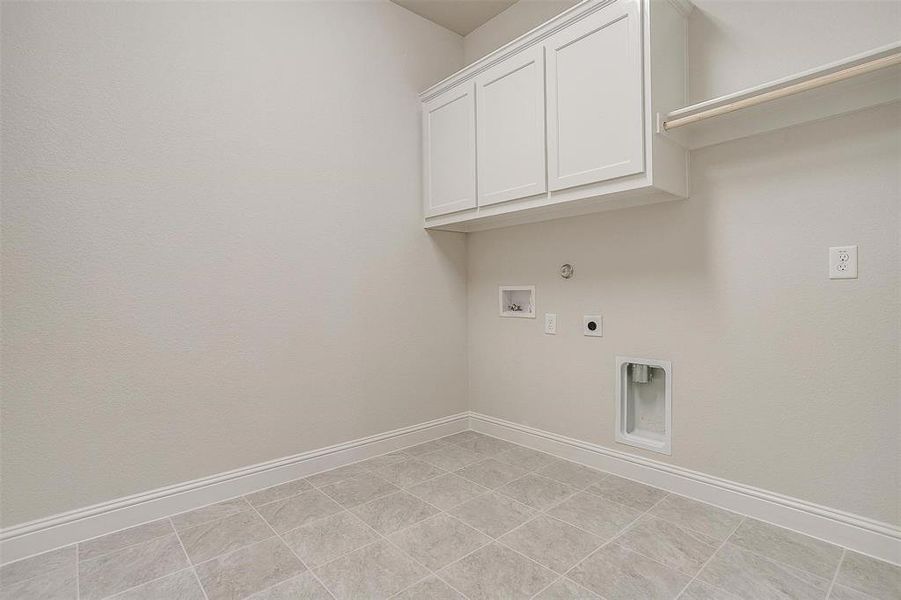 Laundry area featuring light tile patterned flooring, hookup for an electric dryer, washer hookup, and cabinets