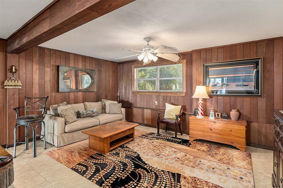 Room featuring wood paneling, an exposed wood beam, and a ceiling fan