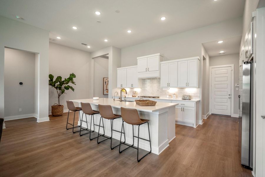 This island kitchen shines with crisp white cabinetry, quartz countertops, subway tile backsplash with under-cabinet lighting and fresh finishes throughout, creating a bright, polished setting for cooking, dining and gathering.