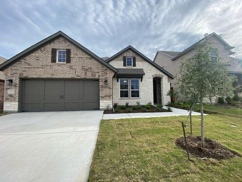 Brick and stone exterior featuring a two-car garage with carriage-style doors Brick and stone exterior featuring a two-car garage with carriage-style doors