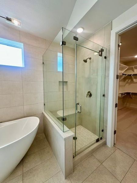 A glass-enclosed shower with a built-in bench and freestanding tub creates a serene bathing space.