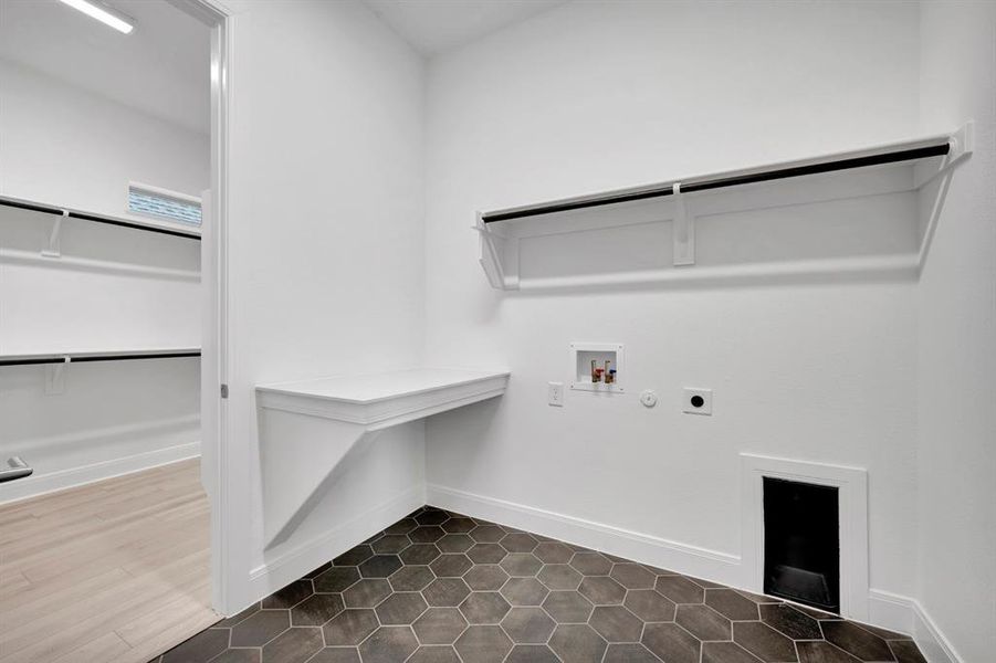 Laundry area with gas dryer hookup, washer hookup, electric dryer hookup, and dark tile patterned floors Laundry area with gas dryer hookup, washer hookup, electric dryer hookup, and dark tile patterned floors